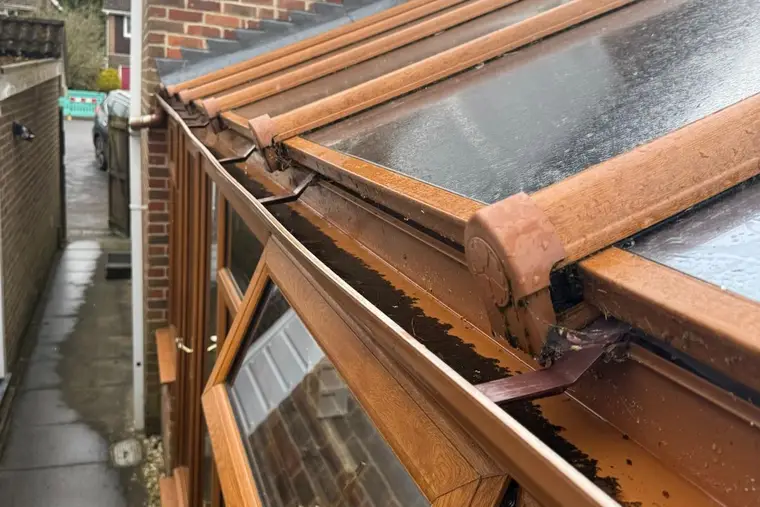 Close view of an oak-effect conservatory with a weathered glass roof