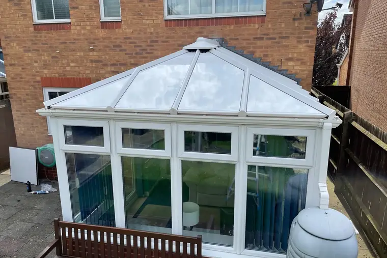Front view of a hipped conservatory roof finished in white insulated panels