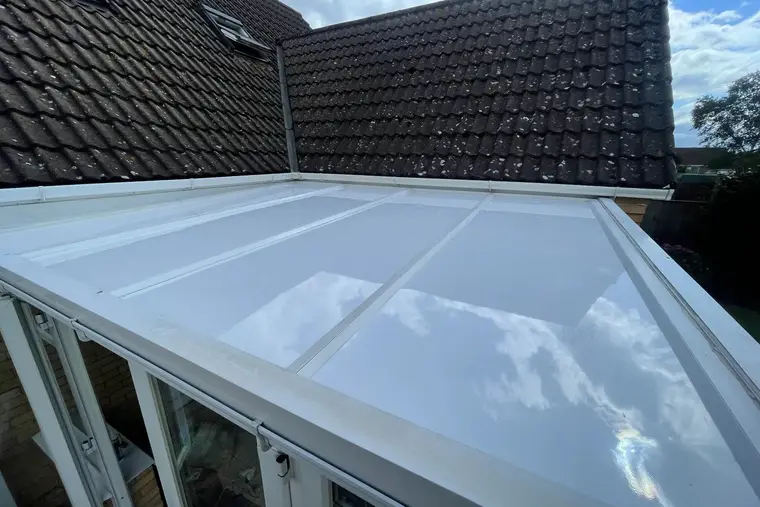 High view along a white insulated panel lean-to roof beside a pitched house roof