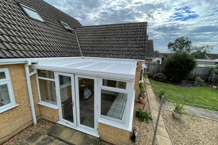 Lean-to conservatory with a white panel roof overlooking a patio and lawn