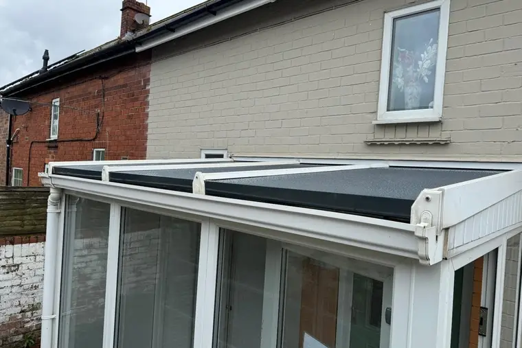 Lean-to conservatory with new dark grey insulated roof panels on white glazing bars