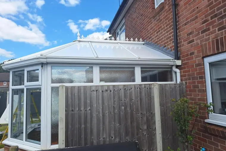 Victorian conservatory with a finished white insulated panel roof on a sunny day