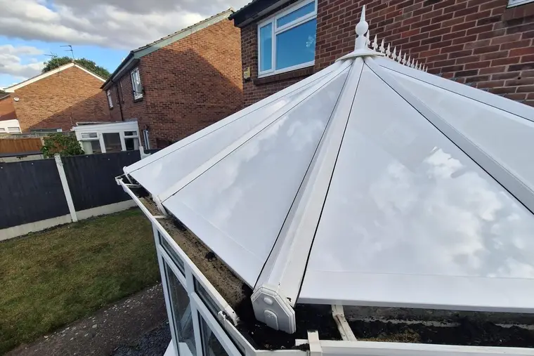 Close view of the glossy white panels and finial on a Victorian conservatory roof