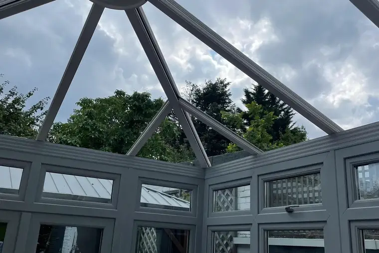 Conservatory roof frame stripped back to the rafters with open sky above, ready for new insulated panels