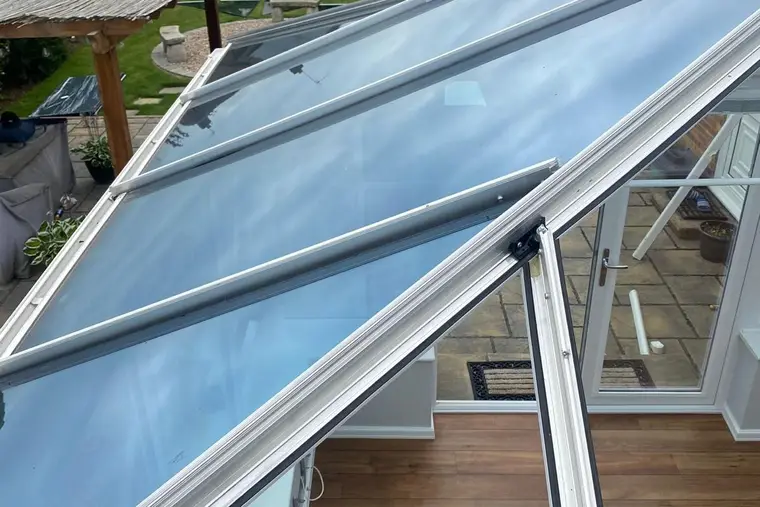 Grey insulated panels being fitted alongside the remaining glass on a conservatory roof