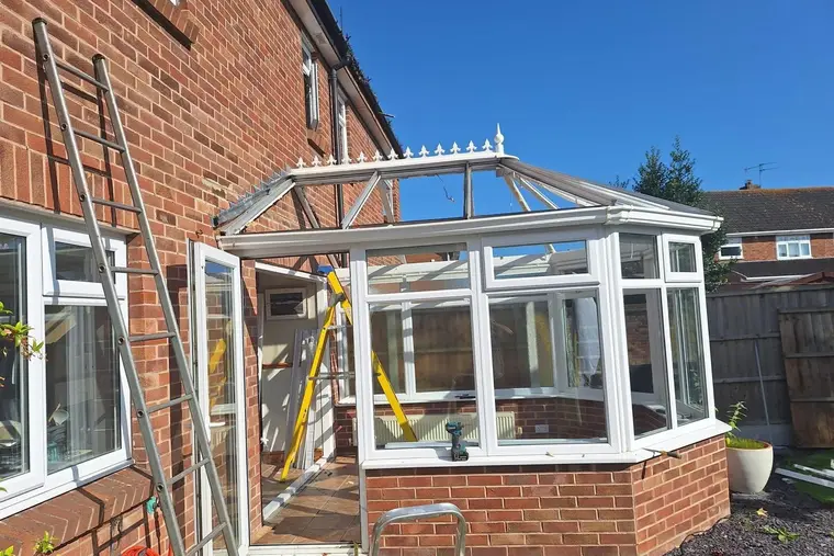 Victorian conservatory with its roof stripped back to the frame and a ladder alongside during installation