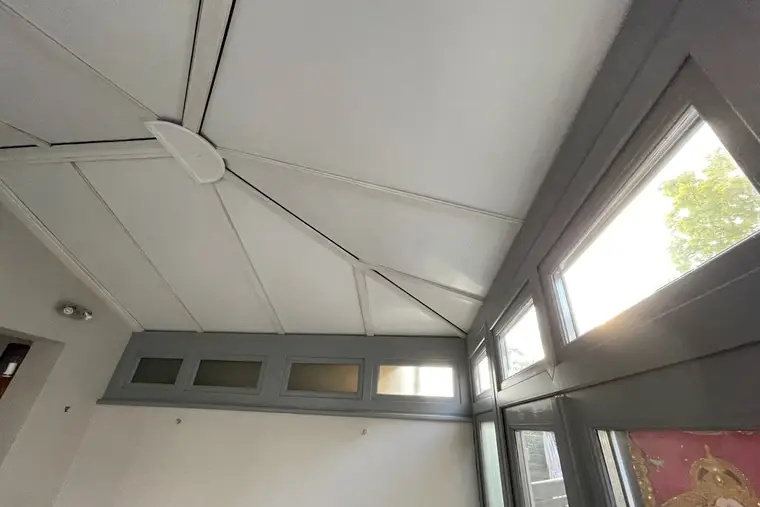 White insulated roof panels meeting at the central hub above grey transom windows