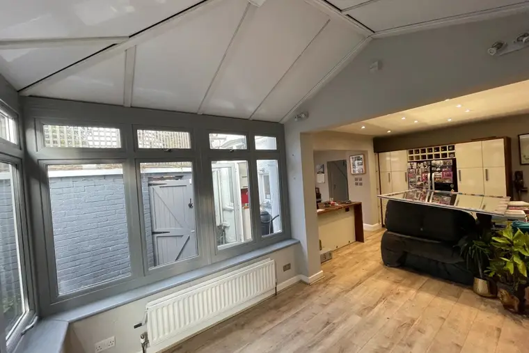 Conservatory with a new white panel ceiling opening through to the kitchen and dining area