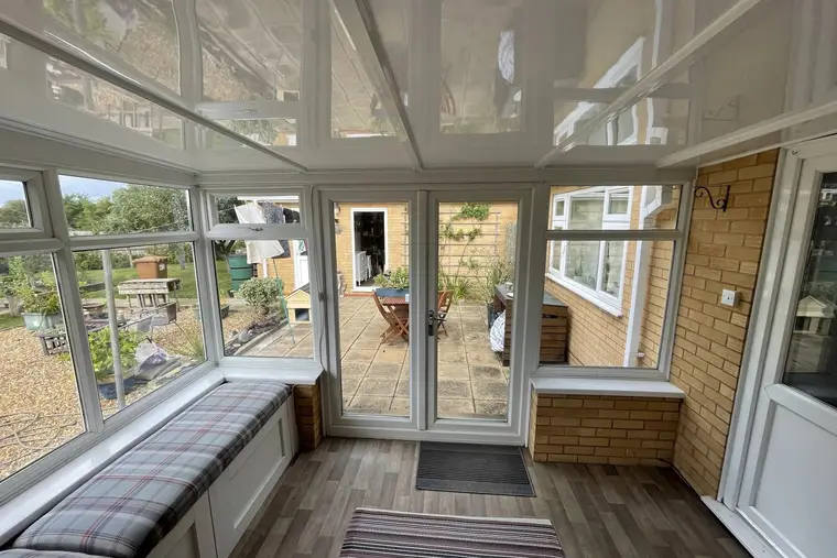 Conservatory with built-in window seats and a glossy white insulated panel ceiling