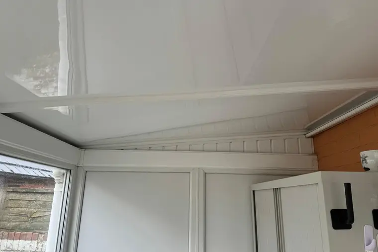 Smooth white insulated panel ceiling inside a small lean-to conservatory